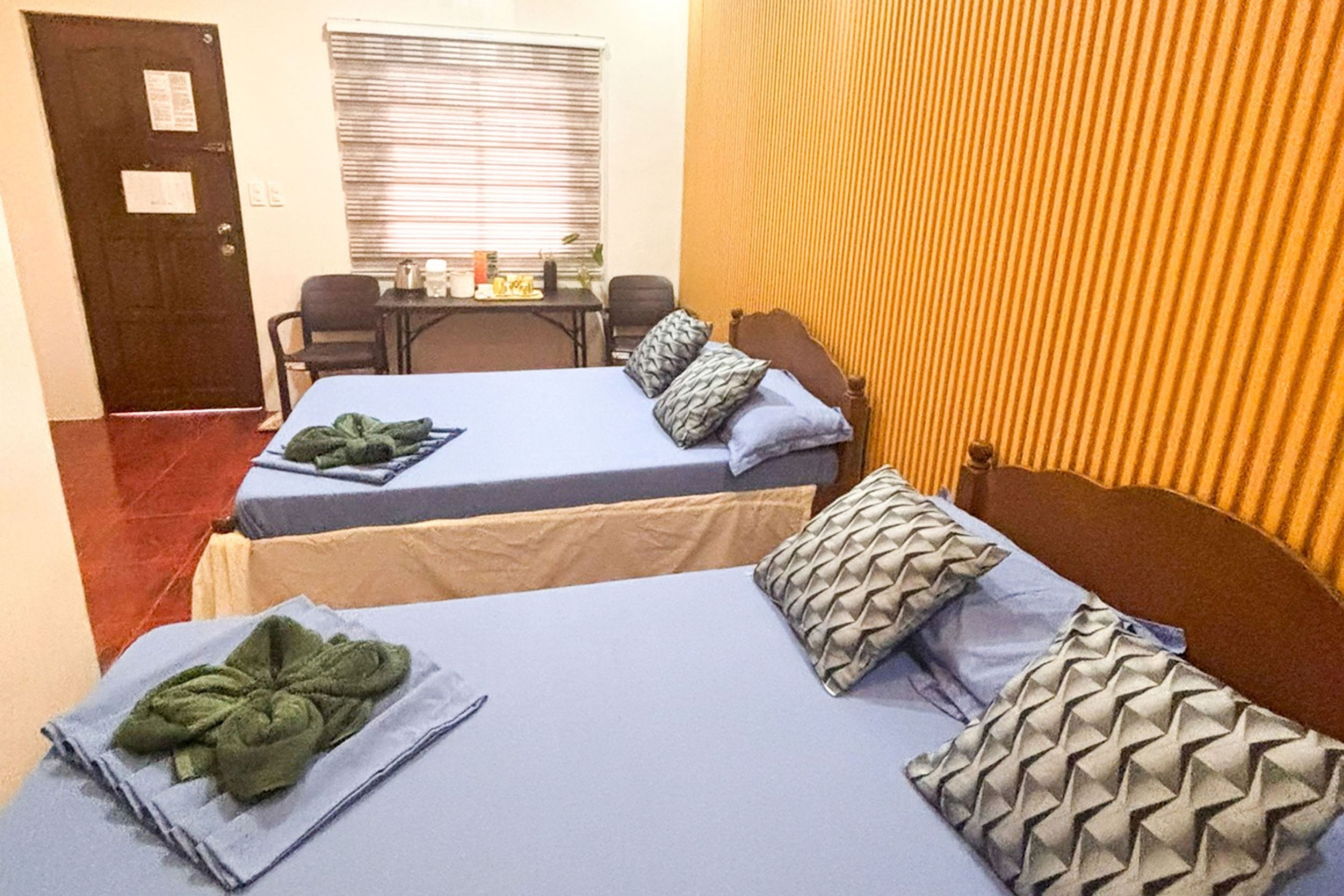 Une chambre d’hôtel avec deux lits, un bureau et une fenêtre avec des stores.