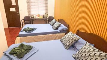 Une chambre d’hôtel avec deux lits, un bureau et une fenêtre avec des stores.