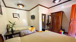 A hotel room with a bed, a desk, a chair, a television, a wardrobe, and a small table with a plant. - Delgados Resort Puerto Galera powered by Cocotel (Puerto Galera)