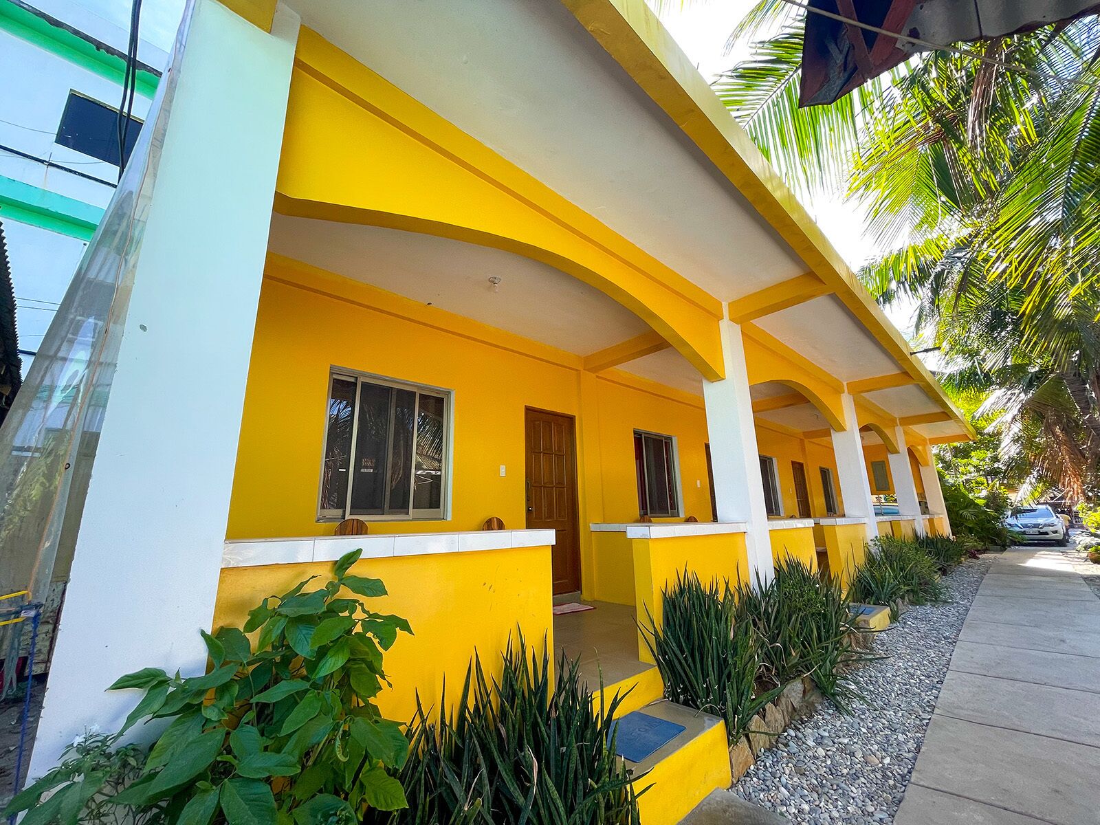 Um edifício amarelo com varanda coberta, janelas e porta.