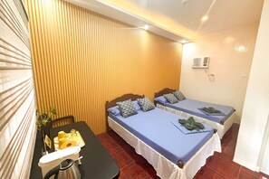 A hotel room with two beds, a small table with a kettle, and a wall-mounted air conditioner. - Delgados Resort Puerto Galera powered by Cocotel (Puerto Galera)