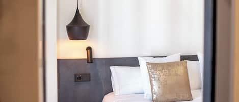A modern bedroom with a bed, a bedside table, a lamp, and a wall-mounted light fixture.
