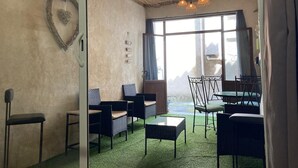 Une pièce chaleureuse, meublée de mobilier en osier, agrémentée d’une décoration en forme de cœur et dotée d’une grande fenêtre offrant une vue sur l’extérieur.