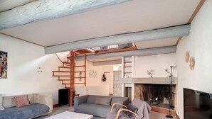 Un salon avec un canapé blanc, un canapé gris, une table basse blanche, une chaise en bois et une cheminée.