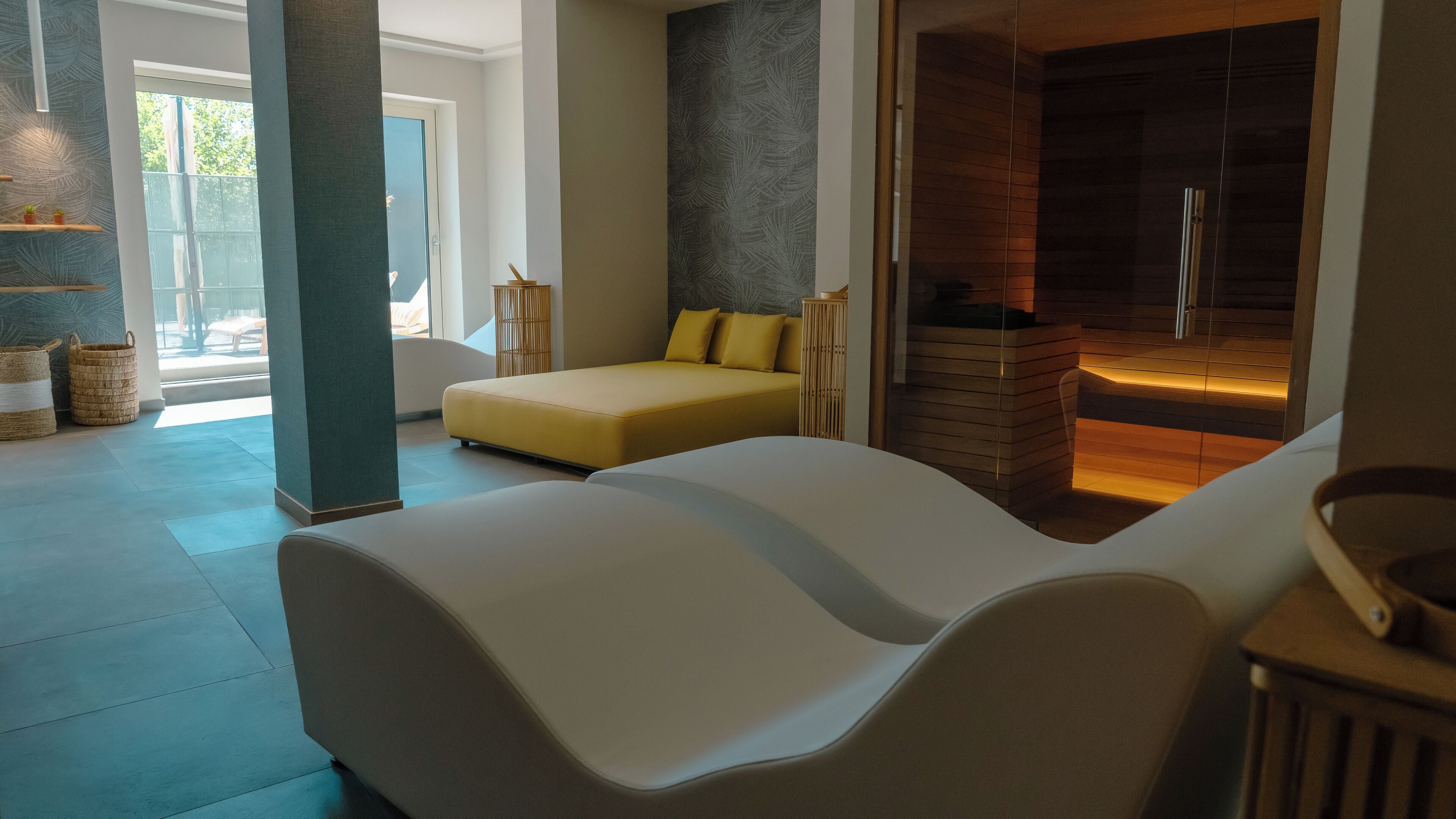 Una moderna sala spa con un ampio divano bianco, una panca gialla e un camino.