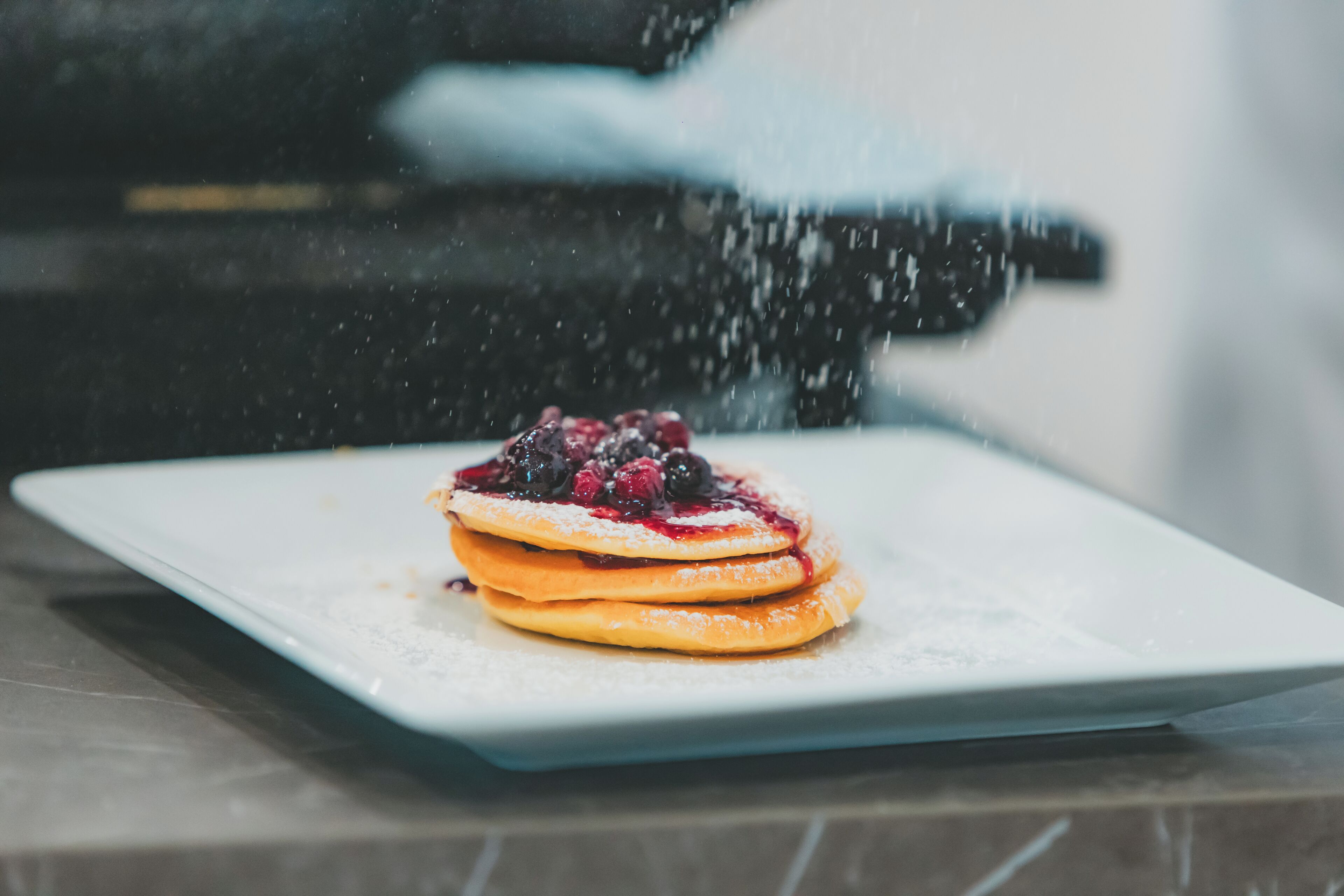 Una pila de tortitas con frutos rojos sobre un plato blanco.