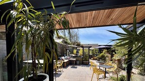 Un espace patio doté d’un sol en pierre, de mobilier d’extérieur et de plantes en pot.