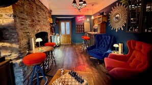 Une pièce chaleureuse avec un mur en briques, une cheminée, un jeu d’échecs et un coin bar.
