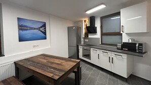 Una cocina moderna con una mesa de madera, armarios blancos, un refrigerador, una estufa y un microondas.
