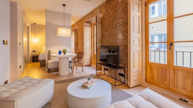Un salon moderne avec un mur en briques, un meuble pour la télévision et une table basse ronde.