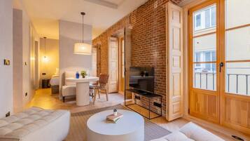Un salon moderne avec un mur en briques, un meuble pour la télévision et une table basse ronde.