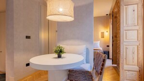 Une chambre d’hôtel moderne avec une table ronde, un banc, une plante en pot et une grande porte en bois.