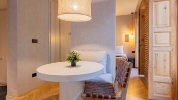 Une chambre d’hôtel moderne avec une table ronde, un banc, une plante en pot et une grande porte en bois.