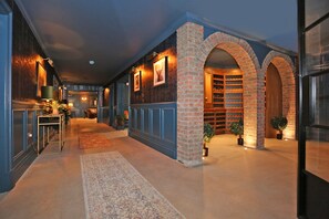 A hallway with a brick archway leading to a wine cellar, a patterned rug on the floor, and a small table with a lamp. - Luxury Manor Private Cinema, Bar, Games & Music Rooms. Perfect for Large Groups (Limerick)