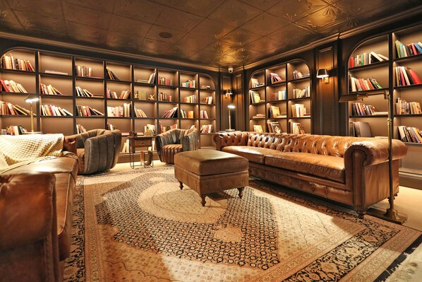 A library with leather sofas, a patterned rug, and bookshelves filled with books. - Luxury Manor Private Cinema, Bar, Games & Music Rooms. Perfect for Large Groups (Limerick)