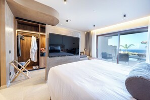 A modern hotel room with a large bed, a walk-in closet, and a balcony with a view of the ocean.