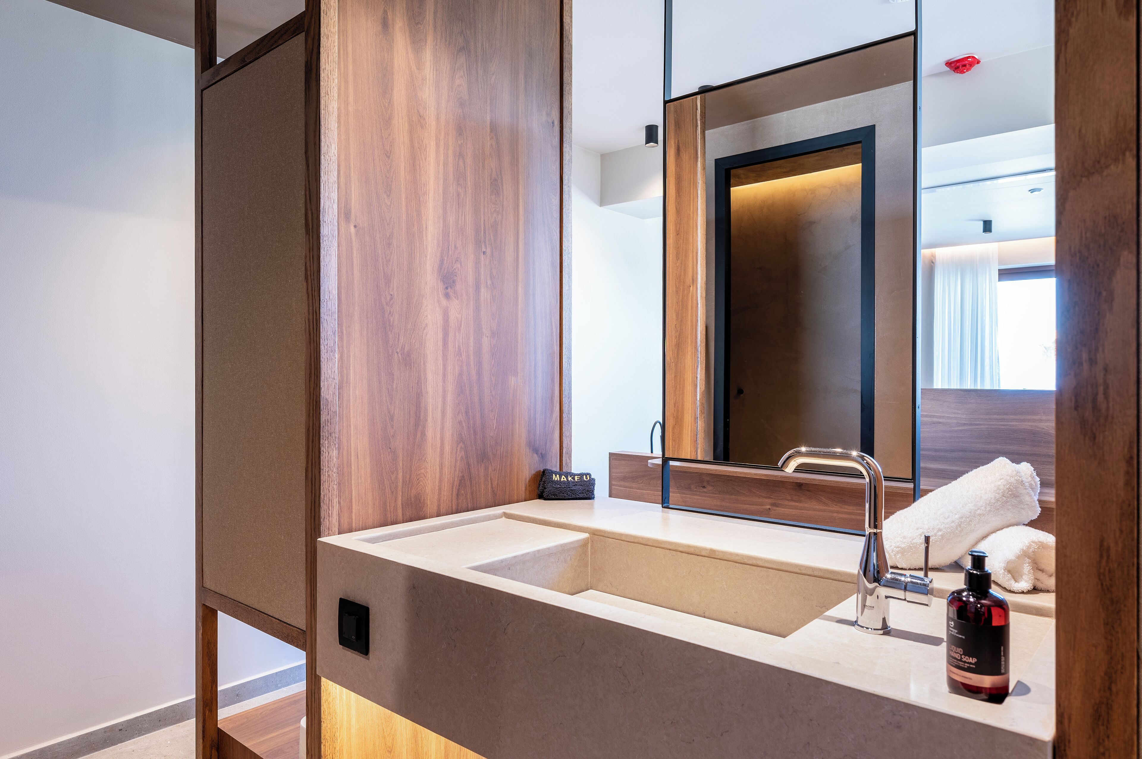 A modern bathroom with a large sink, a mirror, and a towel.