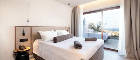 A modern hotel room with a large bed, a bedside telephone, and a view of the outdoors.
