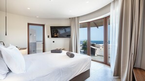 A modern hotel room with a large bed, a flat-screen TV, and a balcony with a view of the sea. - TERRATORRE (Kos)