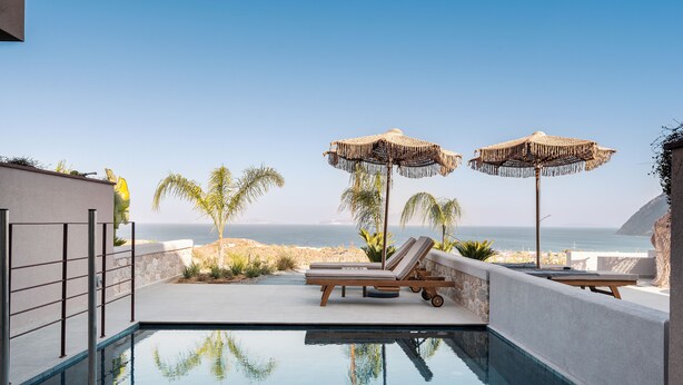 A pool area with lounge chairs and umbrellas, overlooking a beach. - TERRATORRE (Kos)