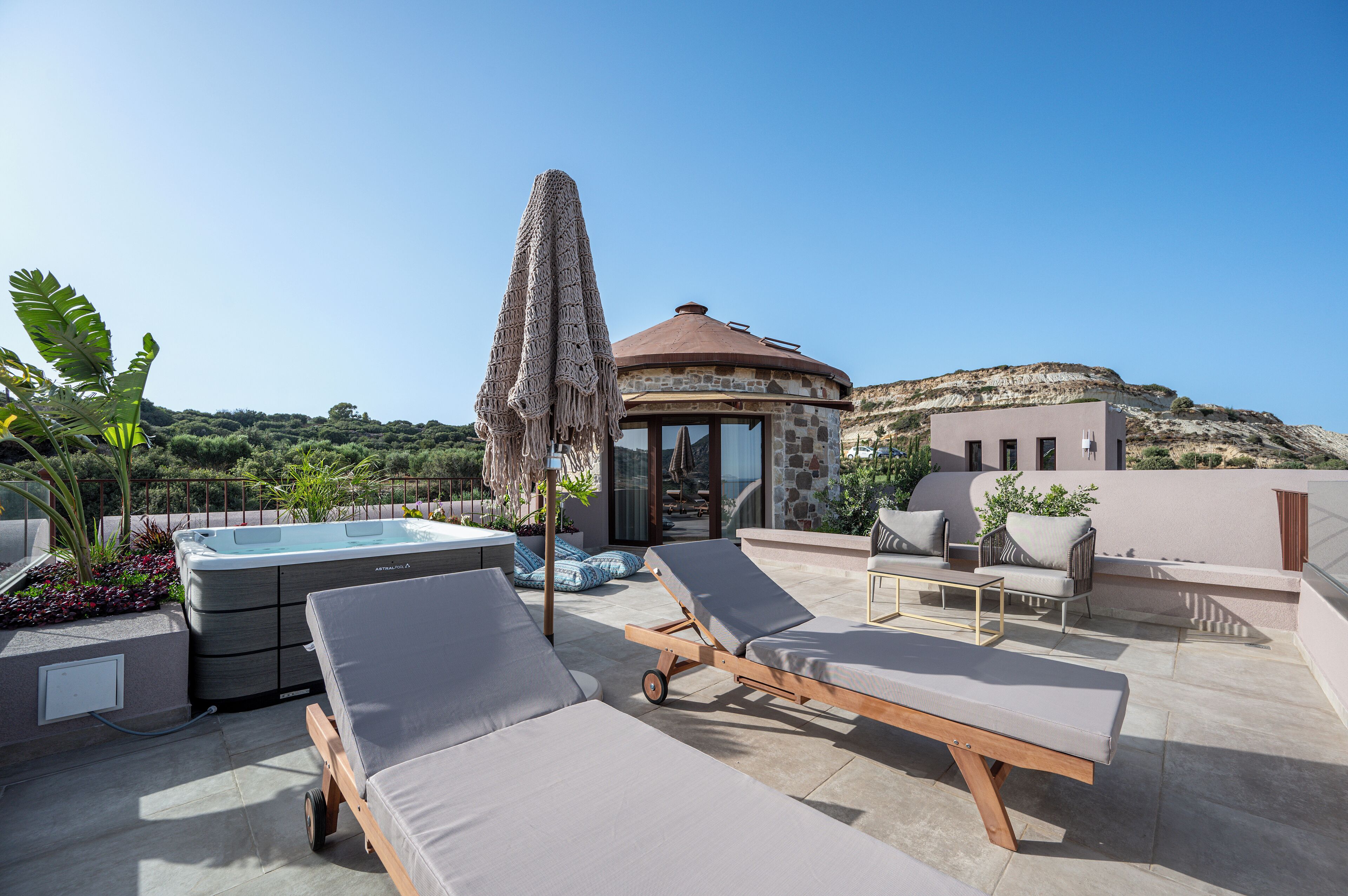 Une terrasse sur le toit avec des chaises longues, un jacuzzi et un espace salon couvert.