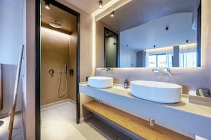 A modern bathroom with two large white sinks, a mirror, and a shower area.