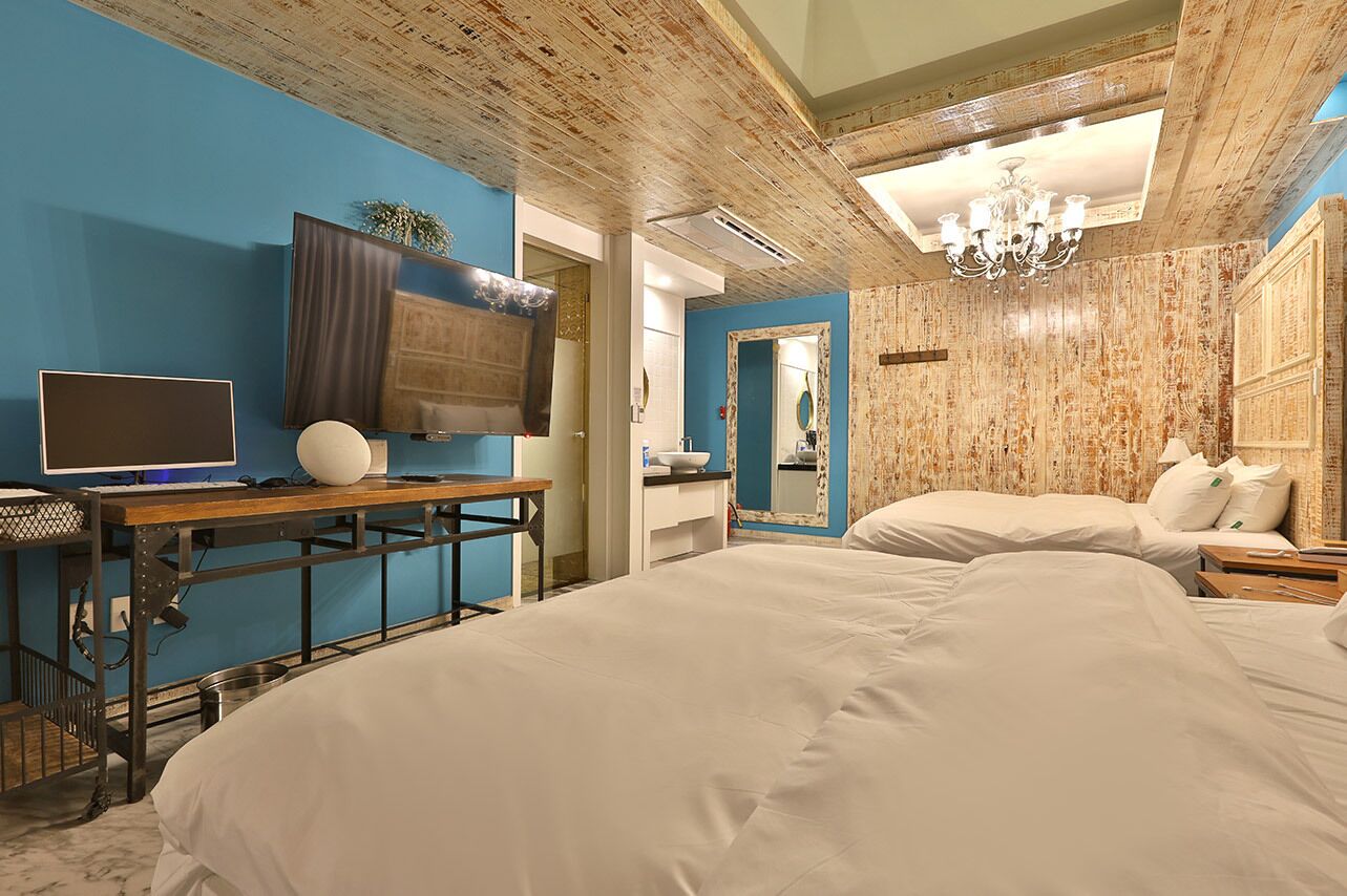 Une chambre d’hôtel avec un grand lit, un bureau avec un ordinateur, une télévision et un lustre.
