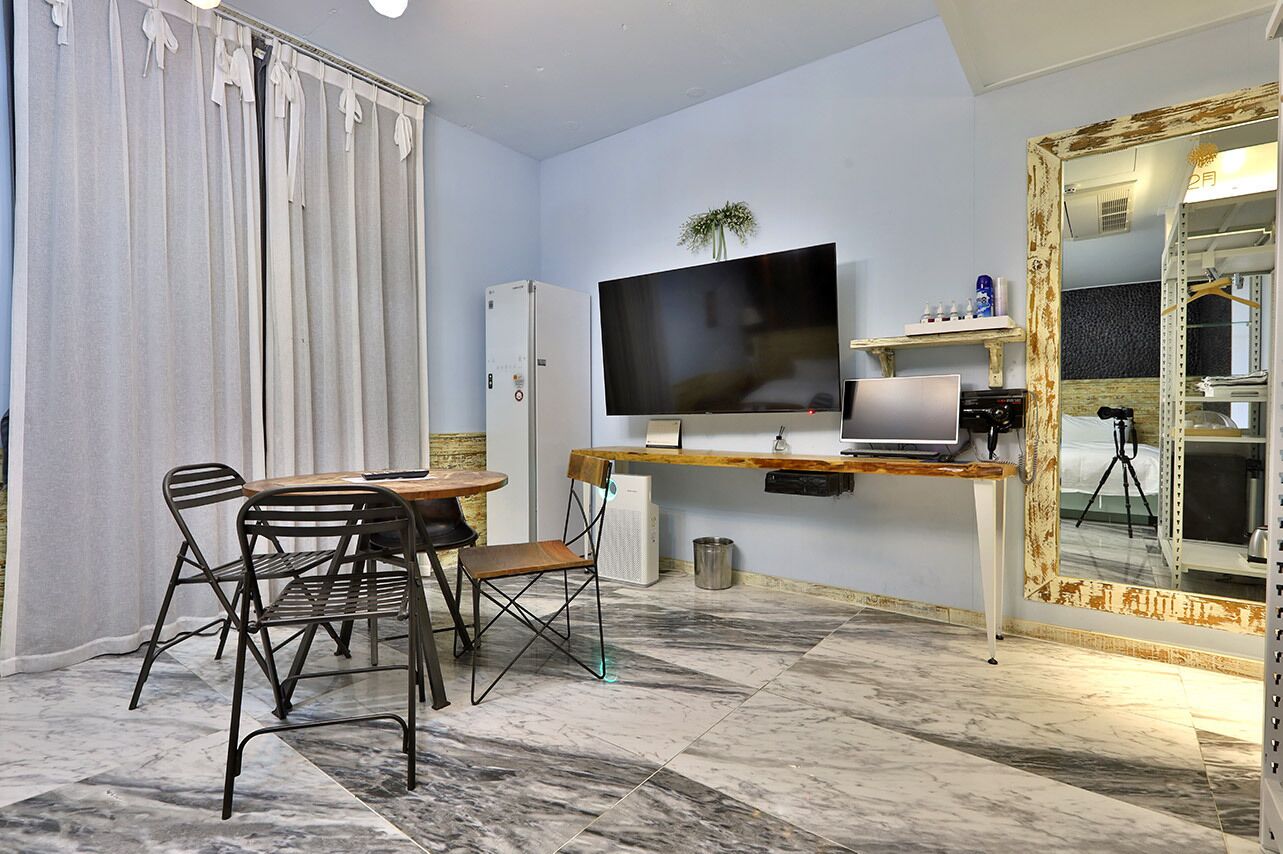 Een moderne woonkamer met een flatscreen televisie, een eettafel met stoelen, een kast en een grote spiegel met decoratieve lijst.