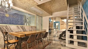 A modern interior with a wooden dining table, chairs, a chandelier, a staircase, and a large mirror. - Hotel February Gimhae (Gimhae)