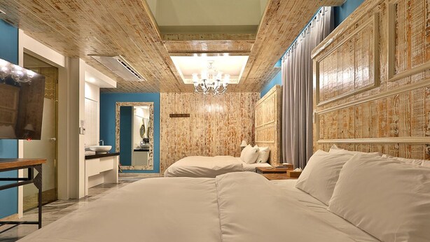 A hotel room with a large bed, a bedside table, a mirror, and a chandelier. - Hotel February Gimhae (Gimhae)