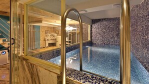A modern indoor pool with a clear glass wall, a pebble-patterned floor, and a wooden ceiling. - Hotel February Gimhae (Gimhae)