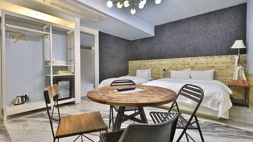 Ein modernes Hotelzimmer mit einem großen Bett, einem runden Holztisch mit Stühlen, einem Kleiderschrank und einer Wand mit besonderer Struktur.