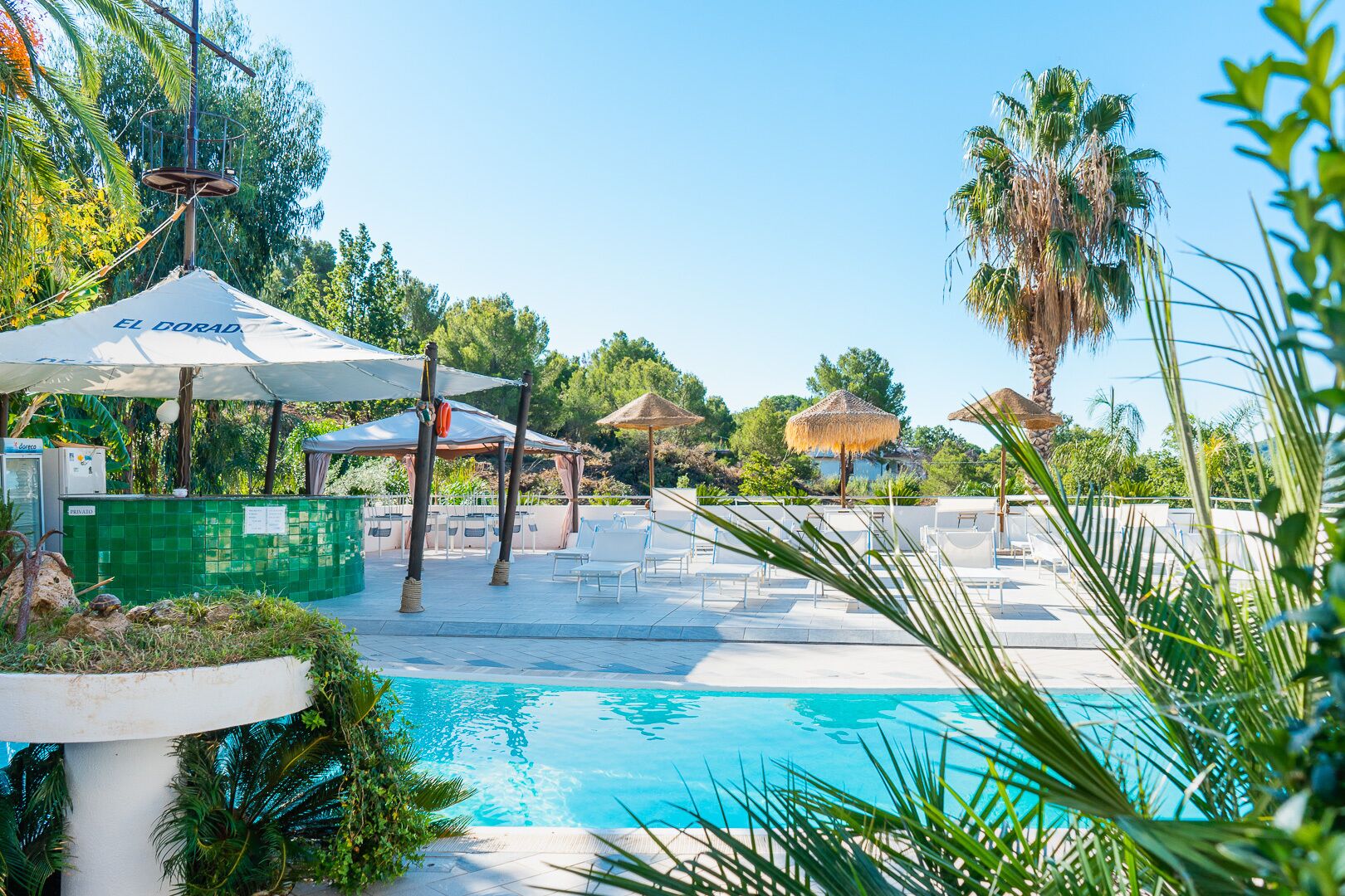 A pool area with umbrellas, lounge chairs, and a clear blue pool.