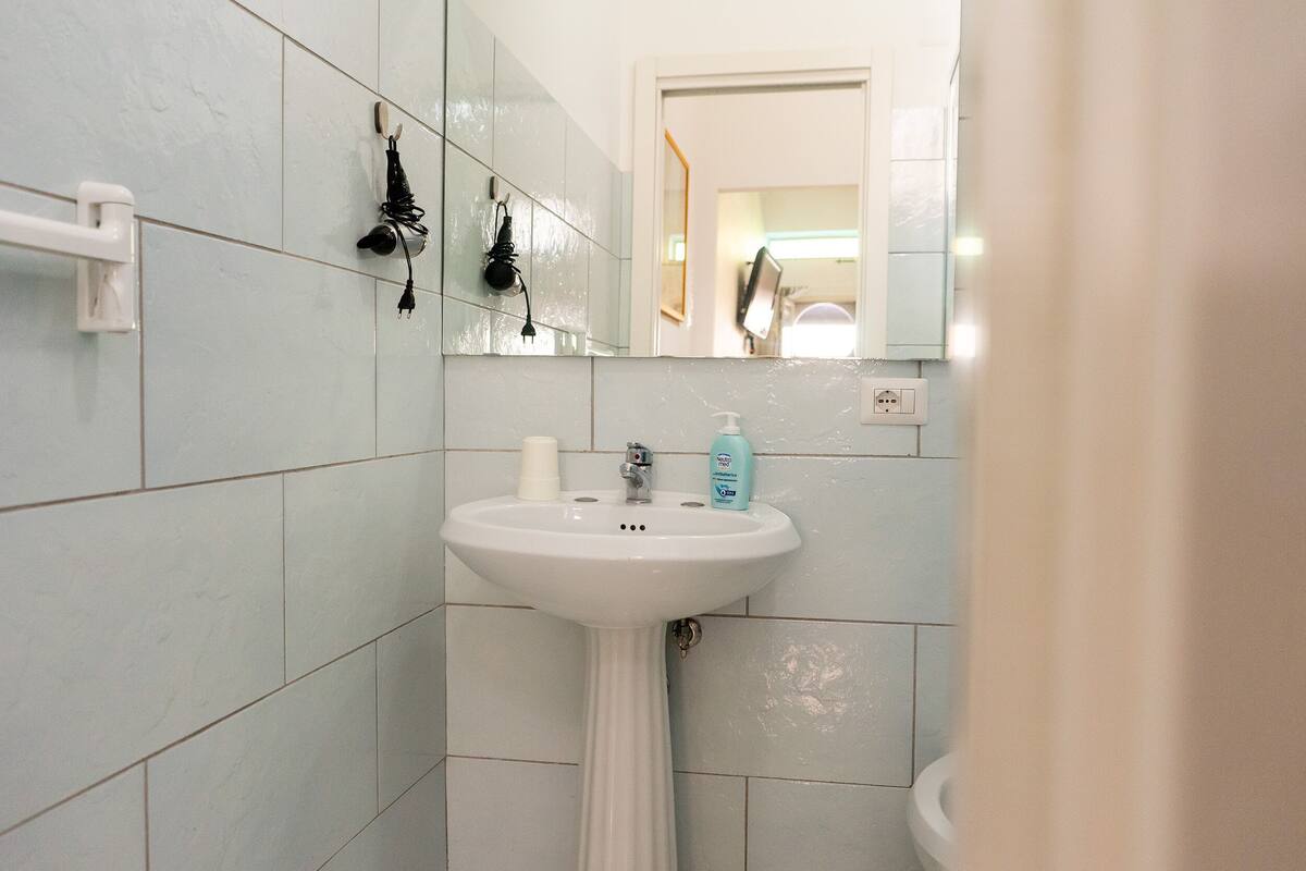 A bathroom with a white sink, a mirror, and a white towel rack.