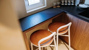 A kitchen with two wooden chairs, a black countertop, and a window.