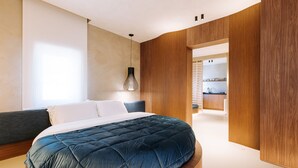 A modern bedroom with a large bed, a wooden accent wall, and a built-in shelving unit in the background.