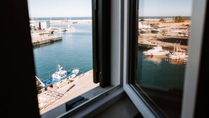 A view of a marina with boats docked at the pier, a clear sky, and a calm sea.