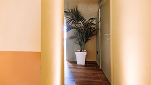 Ein Flur mit einer Blumentopf-Pflanze, Holzboden und einer Tür auf der rechten Seite.