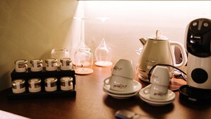 Eine Küchenarbeitsplatte mit Kaffeemaschine, Teekanne, einer Reihe Gläser und einem Teeservice.