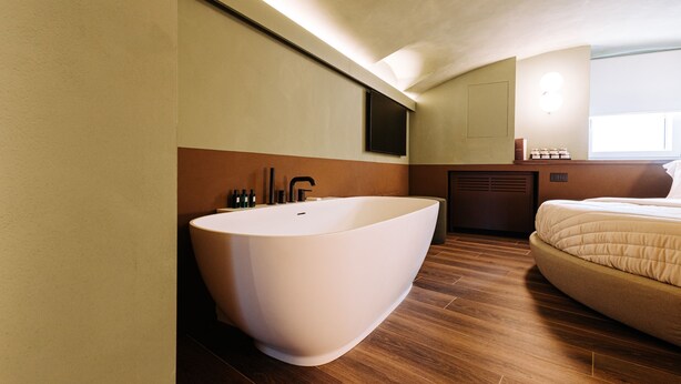 Ein modernes Badezimmer mit einer freistehenden Badewanne, einem großen Spiegel und Holzboden.