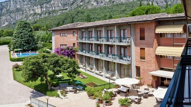 A hotel with a pool, outdoor seating, and a mountain backdrop. - Hotel Gabbiano by Double Hospitality (Garda)