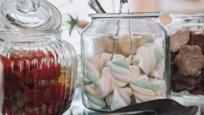 A glass jar filled with colorful candies and a black object on a table. - Hotel Gabbiano by Double Hospitality (Garda)