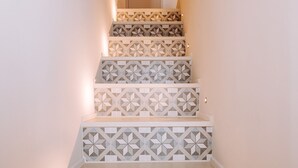 Una escalera con baldosas de diseño geométrico y una lámpara en la parte superior.