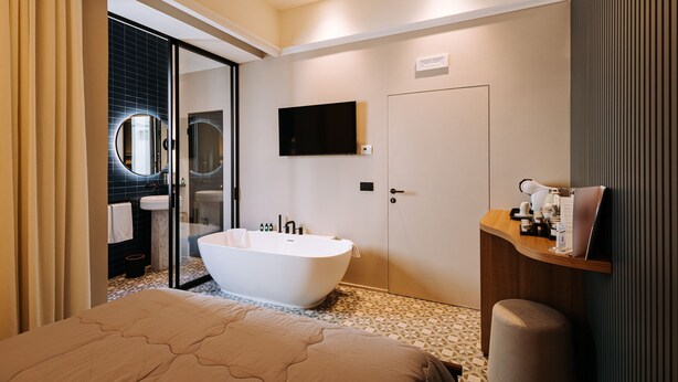 Un baño moderno con una bañera independiente, un espejo grande y un televisor montado.