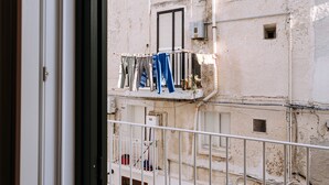 Uitzicht vanuit een gebouw op een balkon met daaraan kleding, een klein raam en een witte balustrade.