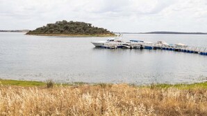 A boat docked near a small island with a grassy foreground. - Sunrise Monsaraz Blue - Casa com 2 Quartos Jardim (Évora)
