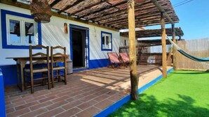 A house with a brick porch, a hammock, and a small garden. - Sunrise Monsaraz Blue - Casa com 2 Quartos Jardim (Évora)