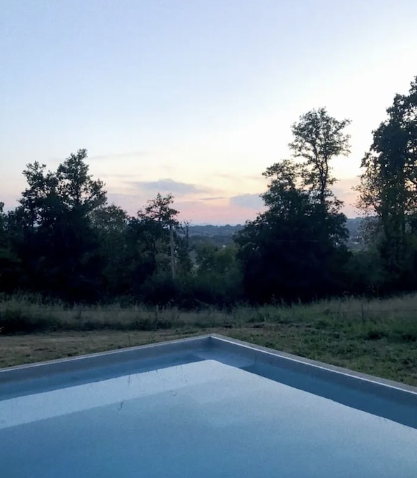 A swimming pool with a clear view of trees and a distant landscape.