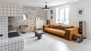 Una sala de estar moderna con una pared de piedra, un sofá de cuero, una mesa de centro y una estantería.