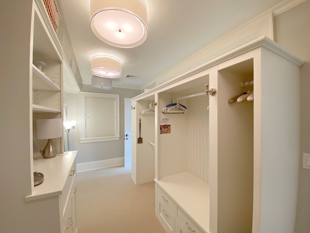 Un vestidor con estantes empotrados, un tocador con espejo y una puerta que da a otra habitación.